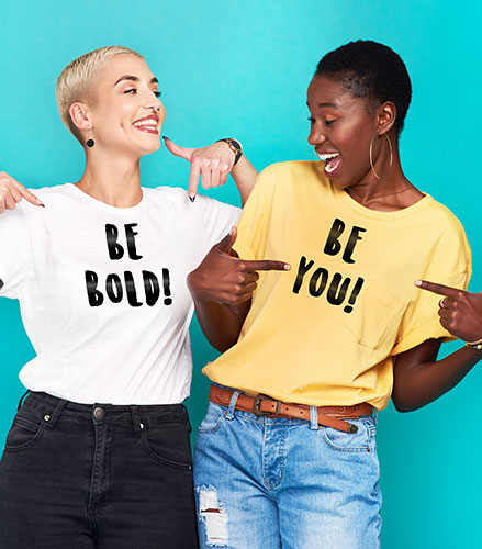 Två kvinnor med t-shirts där det står "be bold" och "be you"
